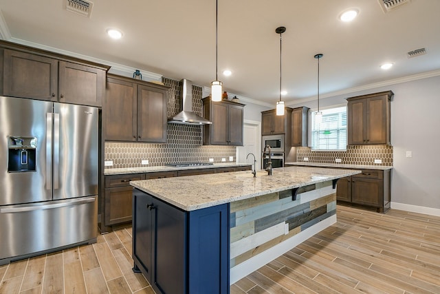 kitchen with crown molding, light wood-style flooring, wall chimney exhaust hood, stainless steel appliances, and visible vents