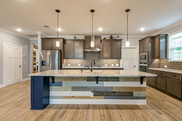 kitchen featuring visible vents, dark brown cabinets, a center island with sink, wall chimney exhaust hood, and appliances with stainless steel finishes