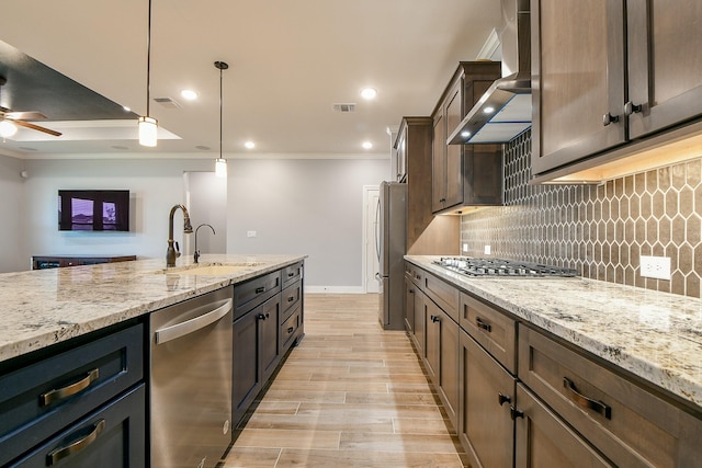 kitchen with wall chimney range hood, crown molding, a sink, stainless steel appliances, and visible vents
