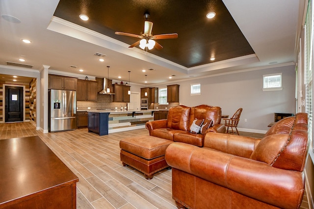 living area with ornamental molding, a raised ceiling, and a wealth of natural light