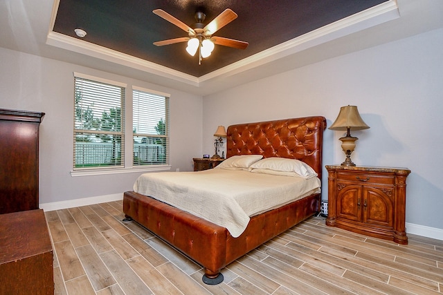 bedroom featuring ceiling fan, a raised ceiling, baseboards, light wood-style floors, and ornamental molding