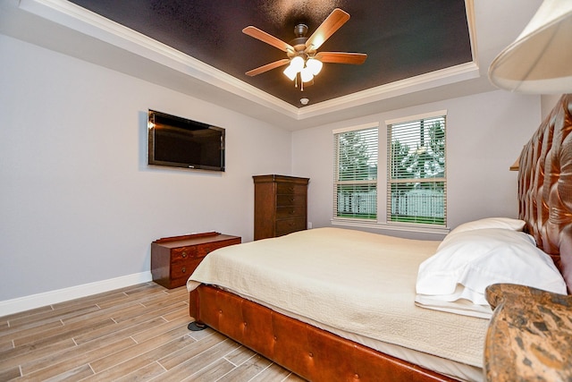 bedroom with a ceiling fan, crown molding, a raised ceiling, baseboards, and light wood-style flooring