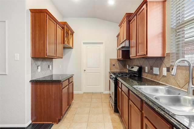kitchen with under cabinet range hood, vaulted ceiling, a sink, stainless steel range with gas cooktop, and brown cabinetry