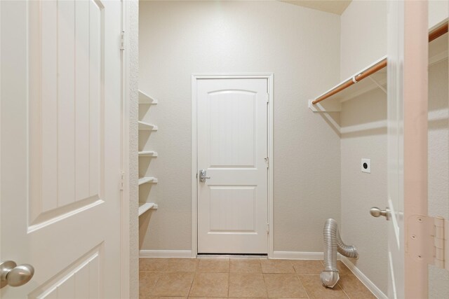laundry area featuring tile patterned floors, baseboards, electric dryer hookup, and laundry area