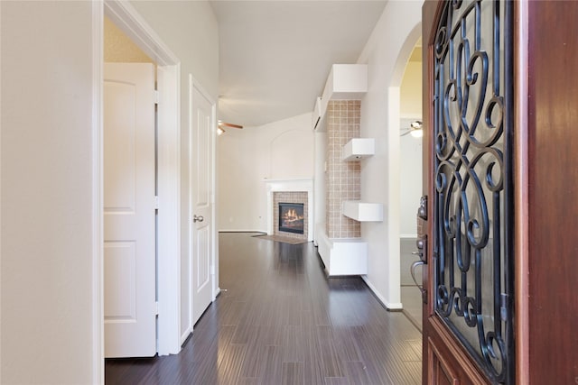 hallway with baseboards, arched walkways, and dark wood finished floors