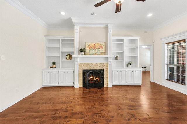 unfurnished living room with dark wood-type flooring, crown molding, baseboards, a tiled fireplace, and ceiling fan