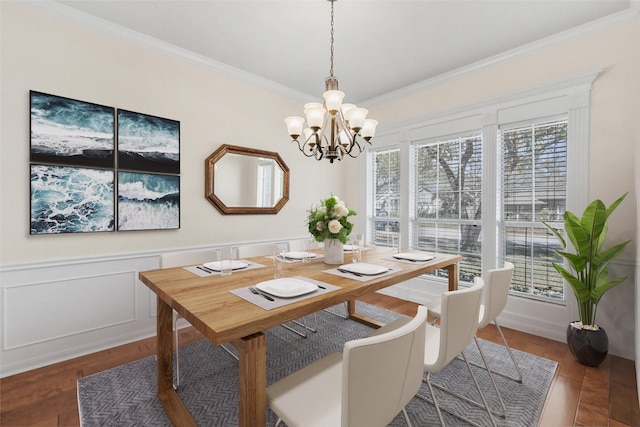 dining room with wainscoting, wood finished floors, an inviting chandelier, and crown molding