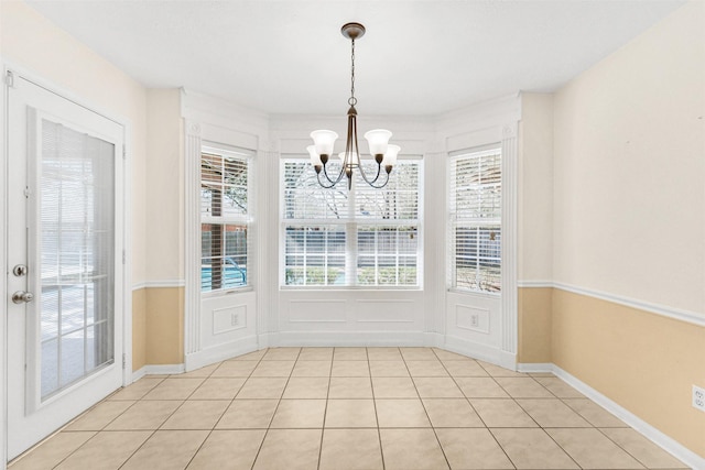 unfurnished dining area featuring light tile patterned flooring, baseboards, and an inviting chandelier