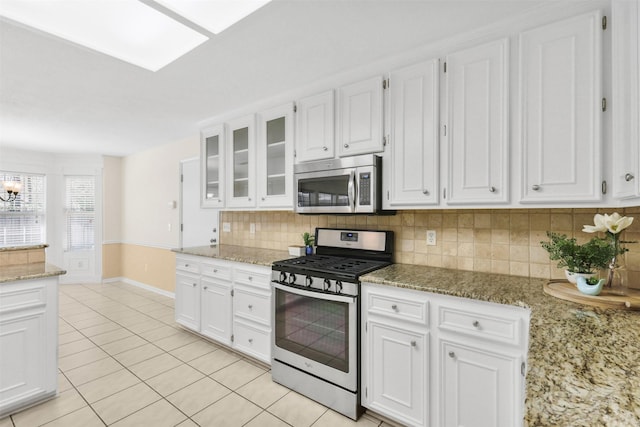 kitchen featuring stainless steel appliances, white cabinetry, light tile patterned floors, and tasteful backsplash