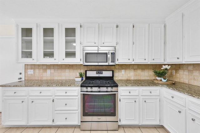 kitchen featuring light stone counters, appliances with stainless steel finishes, light tile patterned flooring, and white cabinetry