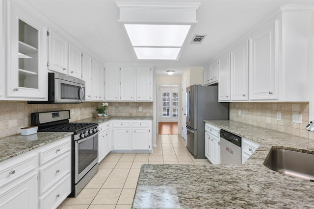 kitchen with stainless steel appliances, a sink, white cabinetry, and light tile patterned flooring