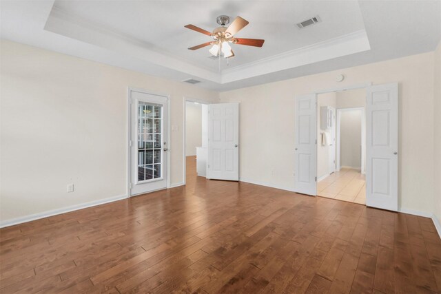 unfurnished bedroom featuring a raised ceiling, baseboards, visible vents, and hardwood / wood-style flooring