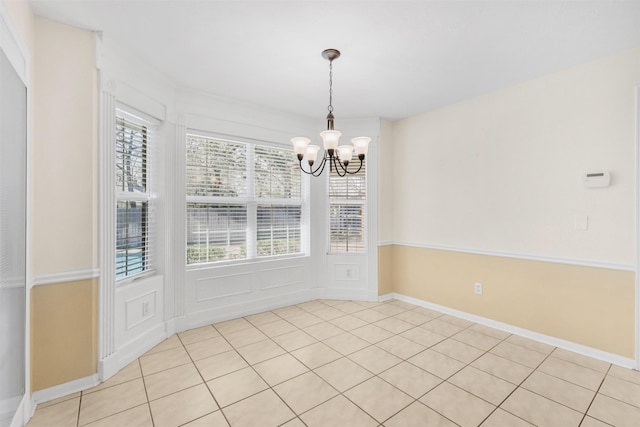unfurnished dining area featuring baseboards, a chandelier, and light tile patterned floors