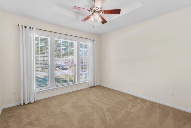 carpeted empty room with a ceiling fan and baseboards