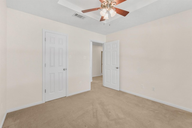 unfurnished bedroom with baseboards, visible vents, light colored carpet, and ceiling fan