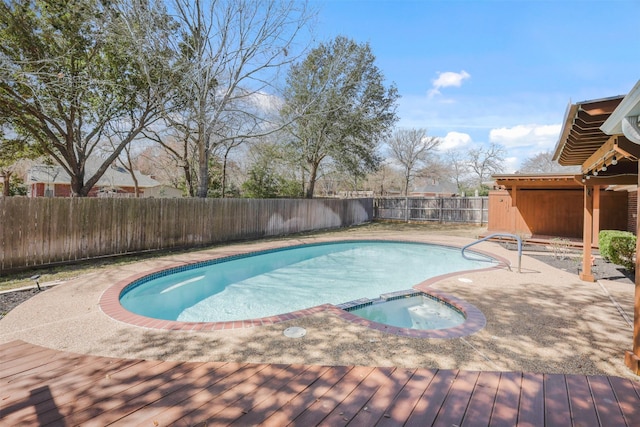 view of swimming pool featuring a pool with connected hot tub and a fenced backyard