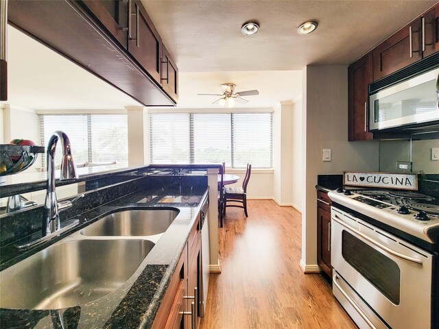 kitchen featuring a sink, light wood-type flooring, baseboards, dark brown cabinetry, and appliances with stainless steel finishes