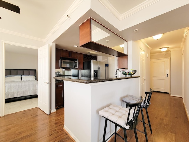 kitchen featuring a kitchen breakfast bar, wood finished floors, dark brown cabinetry, stainless steel refrigerator with ice dispenser, and ornamental molding