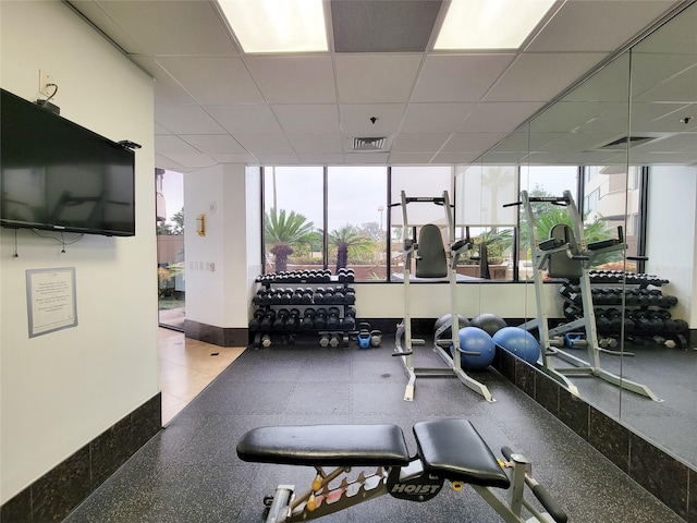 workout area featuring baseboards, a paneled ceiling, and visible vents