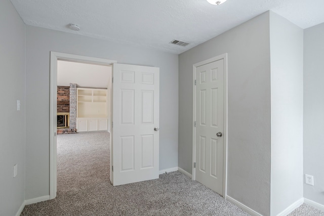 5893 Southern Hills Dr, Houston, TX 77069 - unfurnished bedroom featuring a textured ceiling, a fireplace, baseboards, carpet flooring, and visible vents
