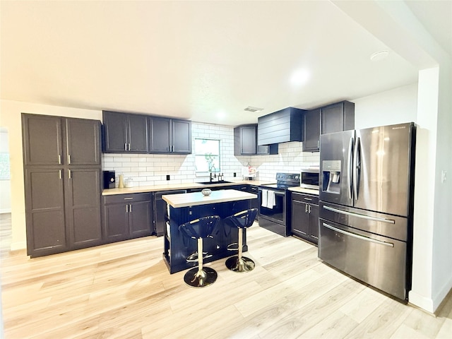 kitchen featuring decorative backsplash, stainless steel appliances, light wood finished floors, and light countertops