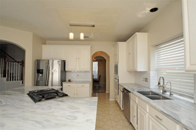 2631 Plantation Hollow Ct, Missouri City, TX 77459 - kitchen with appliances with stainless steel finishes, arched walkways, a sink, decorative backsplash, and light stone counters