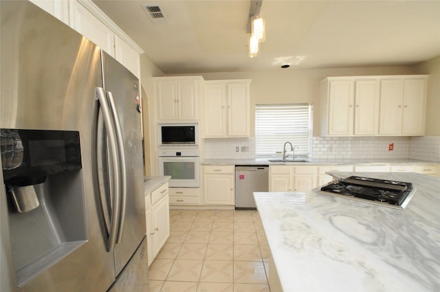 2631 Plantation Hollow Ct, Missouri City, TX 77459 - kitchen with stainless steel appliances, tasteful backsplash, a sink, and white cabinets