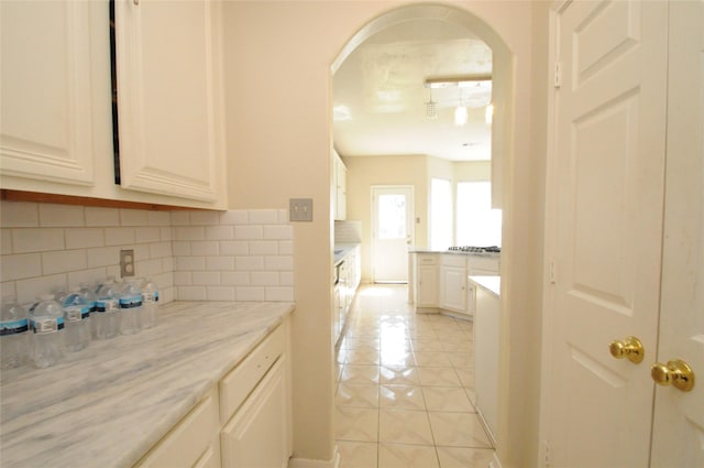 2631 Plantation Hollow Ct, Missouri City, TX 77459 - kitchen with arched walkways, light tile patterned floors, decorative backsplash, and white cabinets