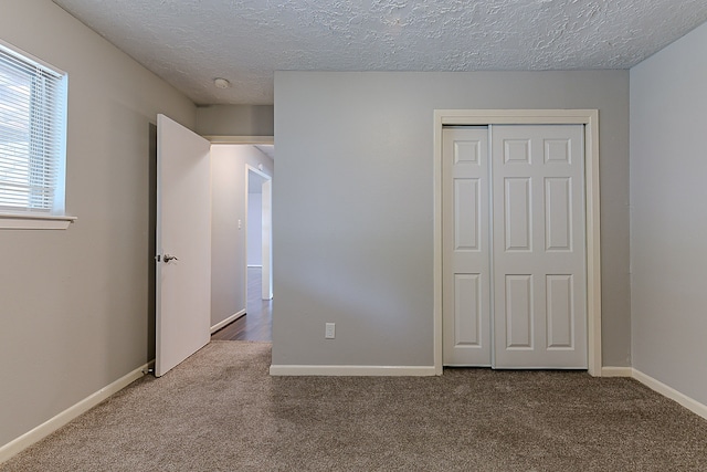 unfurnished bedroom with baseboards, carpet flooring, a textured ceiling, and a closet