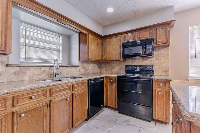 kitchen with tasteful backsplash, light tile patterned floors, a sink, and black appliances
