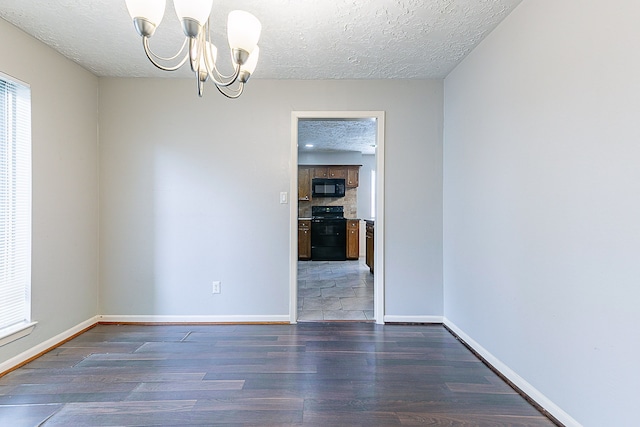 unfurnished room with a chandelier, wood finished floors, a textured ceiling, and baseboards