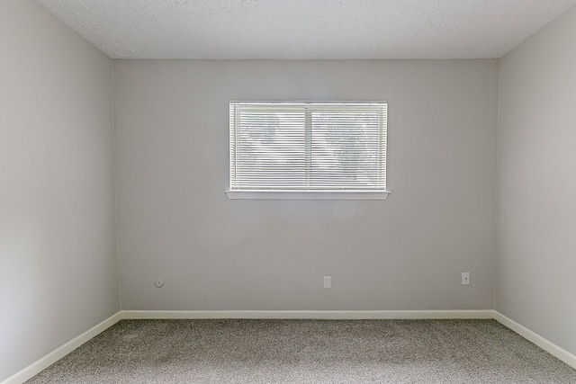 carpeted empty room with baseboards and a textured ceiling