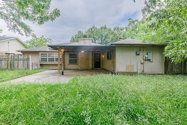 back of house with a chimney, fence, a yard, and a patio