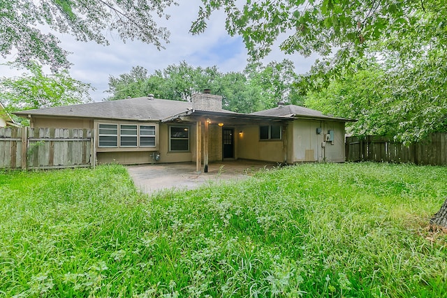 back of property featuring a fenced backyard, a chimney, and a patio