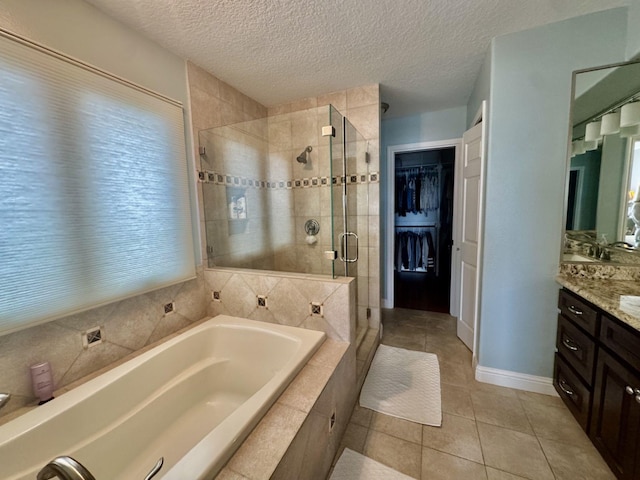 bathroom featuring a shower stall, vanity, a bath, tile patterned flooring, and a spacious closet