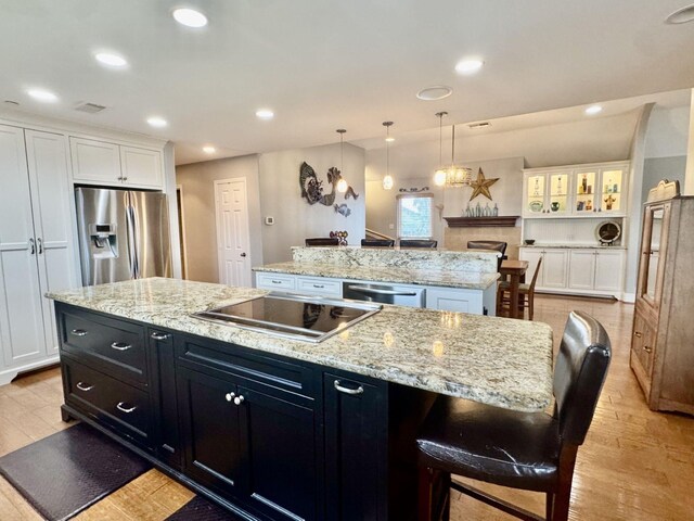 kitchen with appliances with stainless steel finishes, a kitchen island, white cabinets, dark cabinetry, and recessed lighting