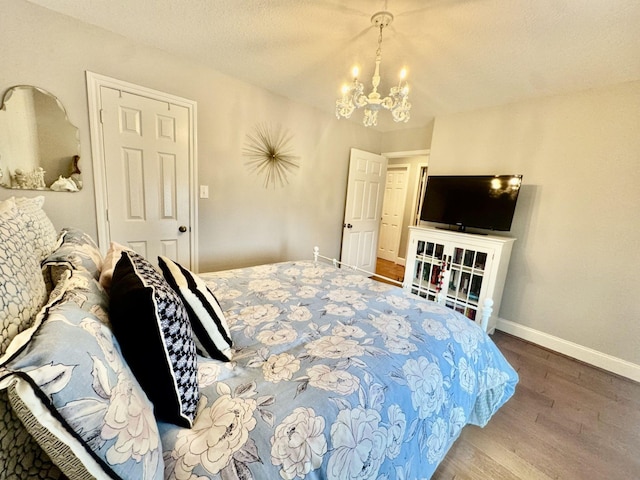 bedroom featuring a chandelier, wood finished floors, and baseboards