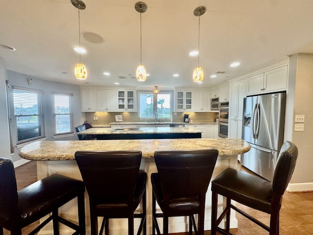 kitchen with stainless steel appliances, a kitchen island, plenty of natural light, baseboards, and recessed lighting