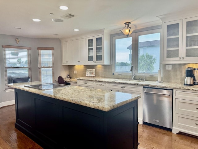 kitchen with dishwasher, a sink, a center island, tasteful backsplash, and wood finished floors