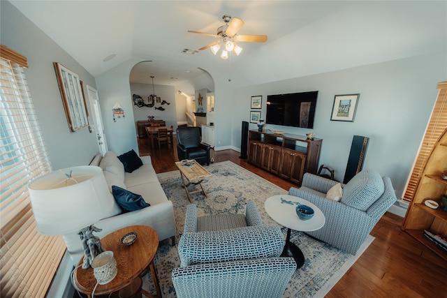 living area featuring vaulted ceiling, a ceiling fan, wood finished floors, baseboards, and arched walkways