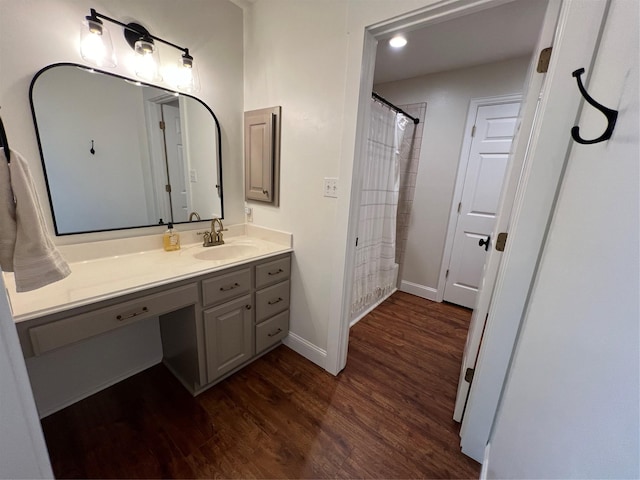 bathroom featuring baseboards, wood finished floors, recessed lighting, and vanity