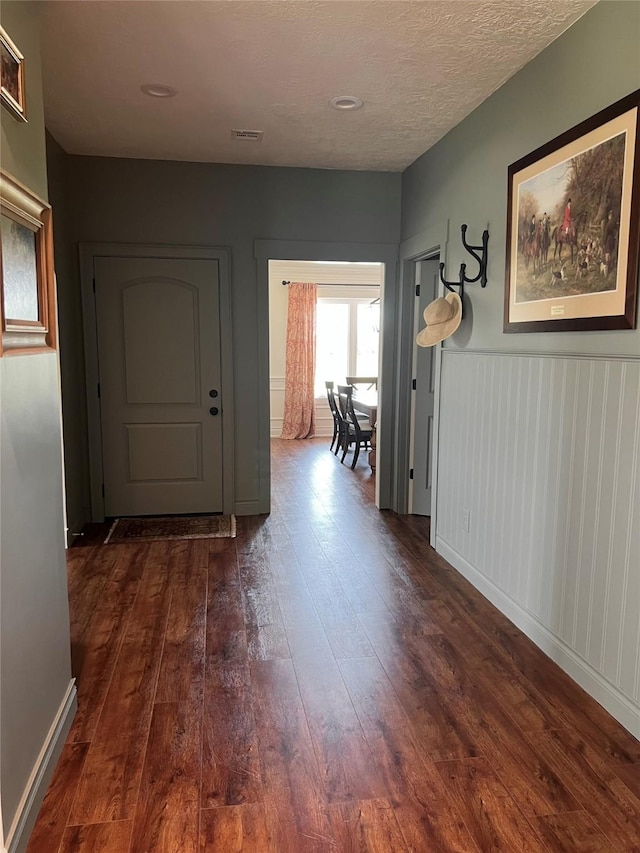 corridor featuring visible vents and dark wood-style flooring