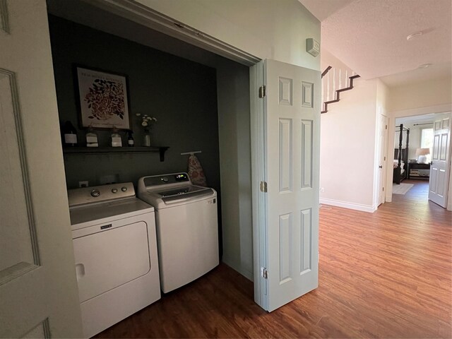 laundry area with dark wood finished floors, washing machine and clothes dryer, laundry area, and baseboards