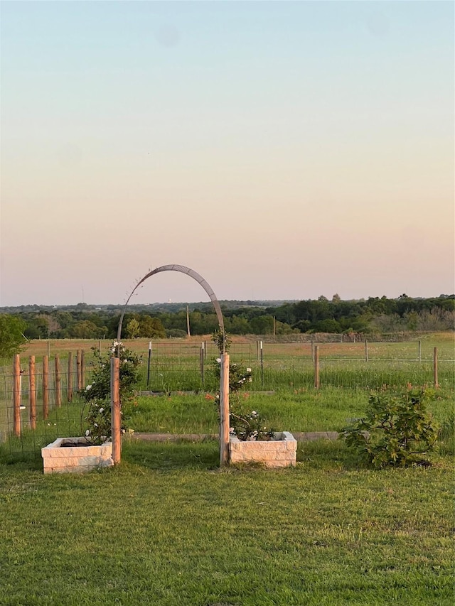 yard at dusk with fence and a rural view