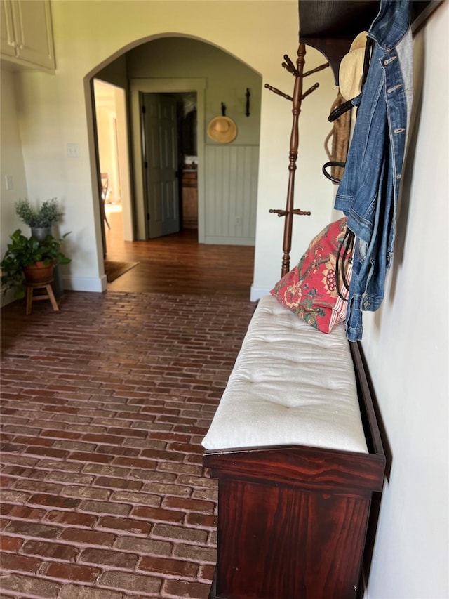 hallway featuring arched walkways and brick floor