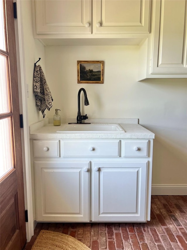 bar featuring brick floor, baseboards, and a sink