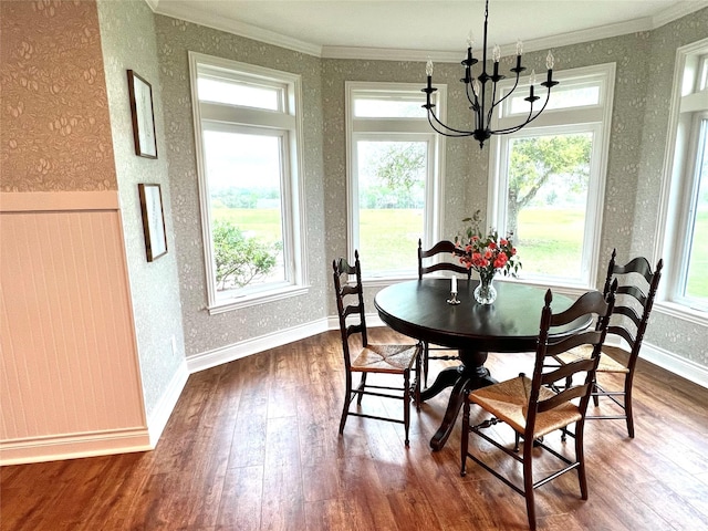 dining area with a wealth of natural light, an inviting chandelier, ornamental molding, and dark wood finished floors