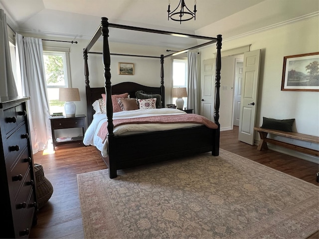 bedroom with dark wood-type flooring, a notable chandelier, and multiple windows