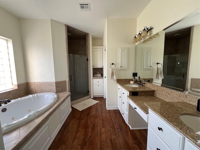 bathroom featuring visible vents, wood finished floors, a whirlpool tub, and a stall shower