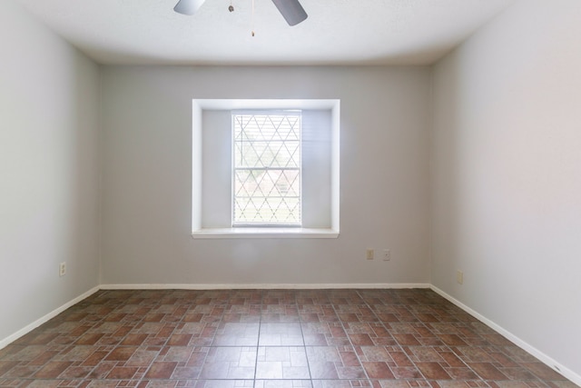 empty room featuring a ceiling fan and baseboards